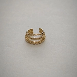 Macro view of a three-tier golden beaded ear cuff with a vintage C-shaped design
