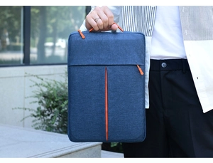 Outdoor shot of a slim navy laptop sleeve with orange accents and reinforced handle