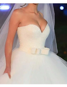 Gros plan sur une robe de mariée blanche à paillettes avec col en V et taille à nœud