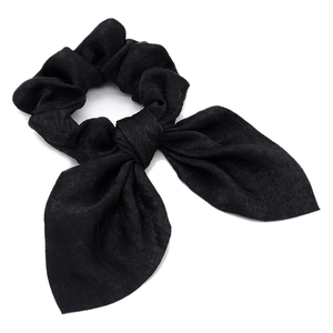Detail of a black satin scrunchie with rabbit ear bow design and textile texture