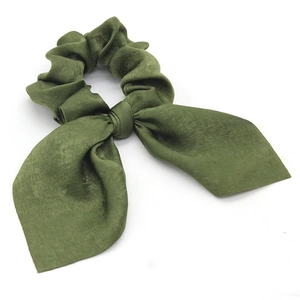 Close-up of a dark green satin scrunchie with long bunny ear bow and smooth texture
