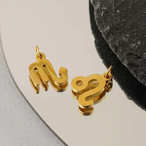 Polished gold stainless steel Scorpio and Leo zodiac pendant charms on a reflective surface