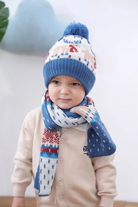 Détail d'un ensemble bonnet et écharpe en tricot bleu clair avec pompons et motifs rouges