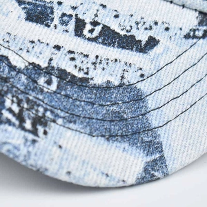 Close-up of the denim baseball cap brim featuring mottled print and five-row stitching