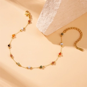 Golden stainless steel chain bracelet with colorful beads and lobster clasp on stone