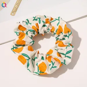 Detailed view of white fabric scrunchie with orange and green citrus fruit pattern