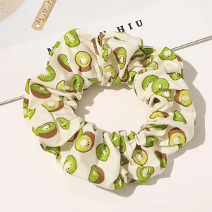Detail of a large cloth scrunchie with green kiwi fruit print on a white background