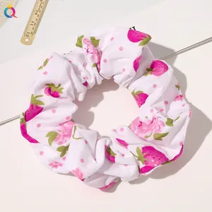 Close-up of white fabric scrunchie with pink strawberry pattern and green leaves