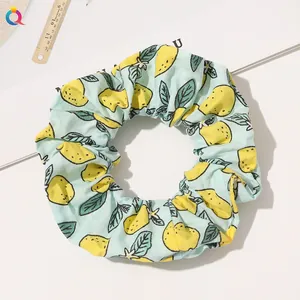 Detailed view of light blue scrunchie with yellow lemon print and cotton fabric texture