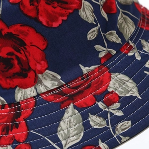 Close-up of navy bucket hat featuring red rose floral pattern and white stitching detail