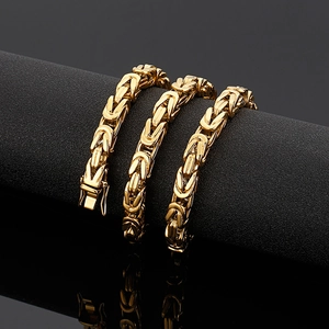 Detailed close-up of golden stainless steel square link chain on black display stand