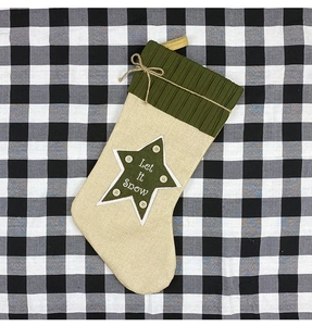 Close-up of linen Christmas stocking with Let it Snow star patch and knit texture