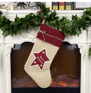 Linen Christmas stocking with red star and Merry Christmas text on a fireplace mantle