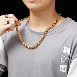 Close-up of a gold Byzantine chain necklace worn by a model with black rings