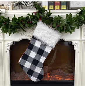 Classic black and white buffalo plaid Christmas stocking with white faux fur trim on fireplace