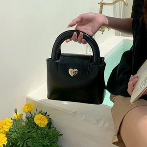Black PU leather handbag with a gold heart lock, stylish minimalist top handle design for women.