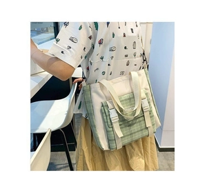 Plaid canvas tote bag with white flap pocket and adjustable strap shown on model