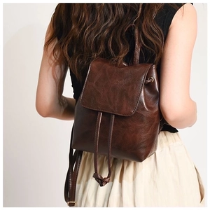 Detail view of the vintage brown leather backpack with drawstring closure on model