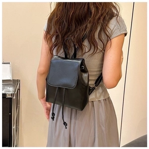 Back view of a black faux leather backpack with drawstring closure on a model