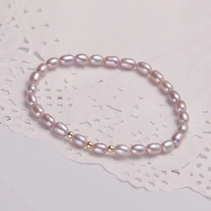 Elegant lavendel zoetwaterparel armband met gouden kralen op een kanten achtergrond