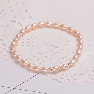 Detail van natuurlijke roze parelarmband met gouden kralen op wit kant achtergrond