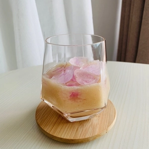 Close-up of geometric glass cup with chilled drink on a round wooden coaster