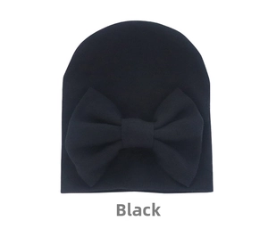 Detailed view of black knitted baby hat featuring a large decorative oversized bow decoration