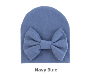 Close-up of navy blue baby beanie with a large bow detail in soft ribbed knit cotton