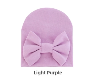 Detail of light purple knit baby hat with a decorative oversized bow on white background
