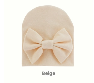 Detail of soft beige knit baby hat featuring a large decorative bow for newborns