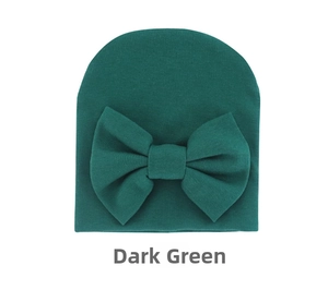 Macro shot of dark green ribbed knit baby beanie featuring a large decorative bow detail