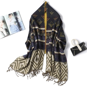 Detail of geometric pattern scarf with navy, yellow, and red tassels on white background
