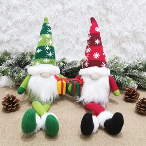 Dettaglio di gnomi di Natale senza volto rossi e verdi con gambe lunghe su sfondo nevoso