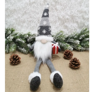 Dettaglio di gnomo natalizio a gambe lunghe con cappello a fiocchi e pacco regalo