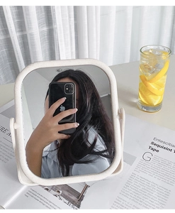 Detail of beige desktop vanity mirror with adjustable stand on a newspaper background