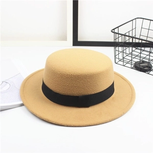 Close-up of a camel wool flat top boater hat with a black grosgrain ribbon detail