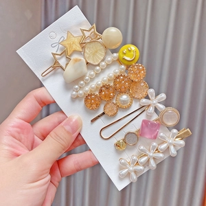 Detail of 8-piece pearl hair clip set featuring golden star and floral resin designs