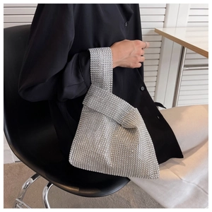 Close-up of sparkling silver rhinestone evening handbag with a ring handle on a model