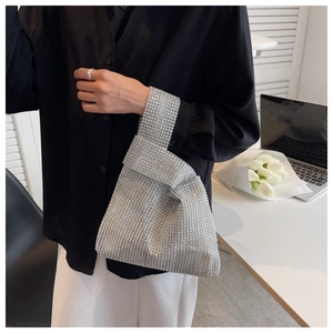 Detail of silver rhinestone mesh handbag on a minimalist desk with elegant accessories