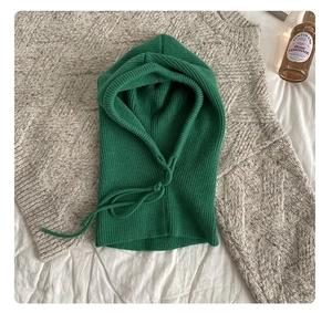Detail of green ribbed balaclava hood with drawstring on a beige knit sweater