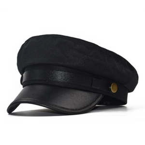 Close-up of black military flat top hat with fabric texture and gold button detail