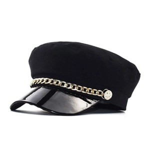 Close-up of black baker boy hat with golden metal chain and glossy patent leather brim