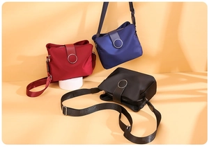 Three multi-layer nylon crossbody bags shown in red, blue and black with wide straps