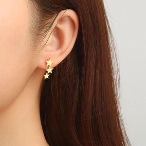 Three-star stainless steel stud earrings in 18K gold finish on ear model