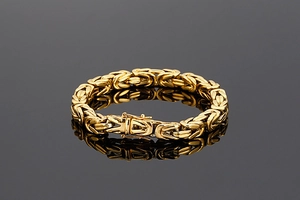 Détail d'un bracelet byzantin doré avec fermoir pliable posé sur une surface réfléchissante noire
