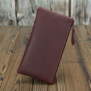 Detailed view of deep red-brown crazy horse leather wallet with secure zipper on wooden desk