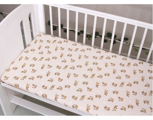 Close-up of baby crib sheet featuring a cute cartoon lion pattern on cream fabric
