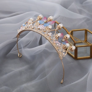 Close-up of golden tiara with pearls, colorful crystals, and gradient butterfly details