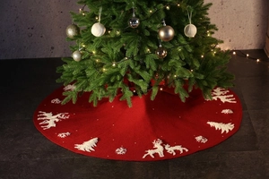 Detail of red Christmas tree skirt featuring embroidered reindeer and snowflakes