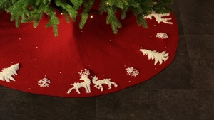 Detail of red knitted Christmas tree skirt featuring white elk and tree patterns